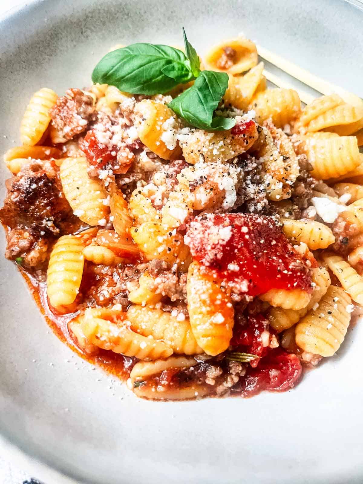 Malloreddus alla campidanese garnished with basil.